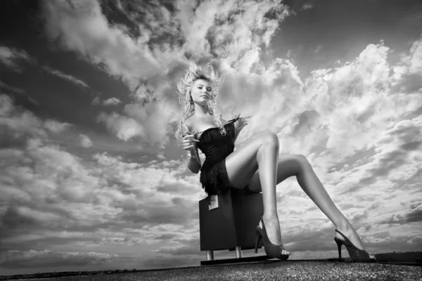 Gyönyörű lány ül egy felhős ég ellen — Stock Fotó