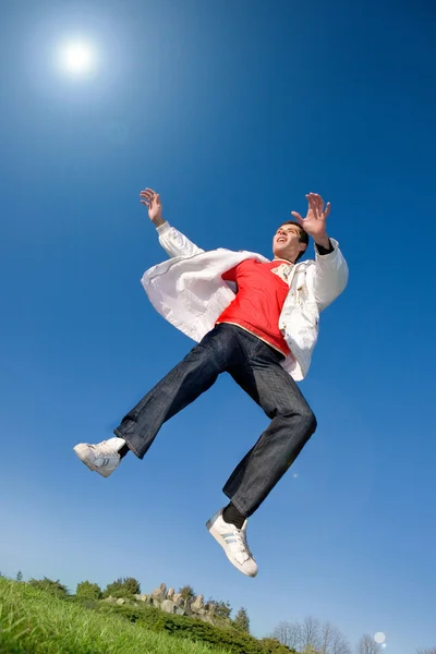 Χαρούμενος νεαρός άνδρας - άλμα τέλος μύγες στο γαλάζιο του ουρανού — Φωτογραφία Αρχείου