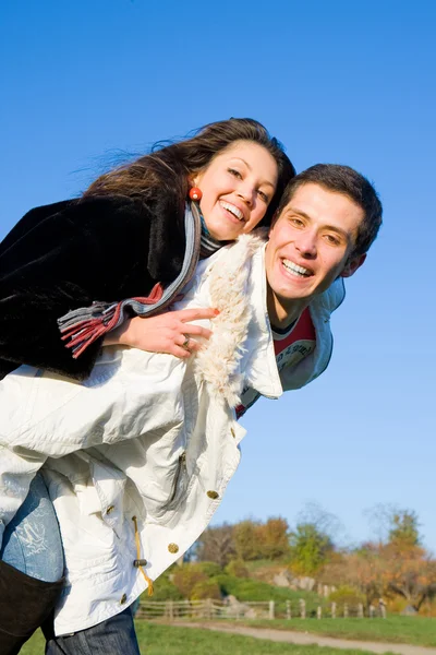 Mladá láska pár usmívající se konec létat pod modrou oblohou — Stock fotografie
