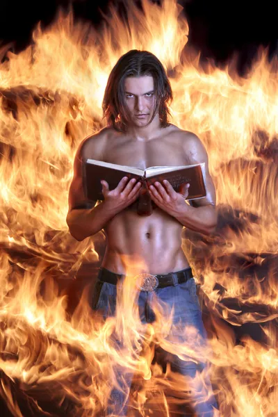 Brawny el hombre sostiene el libro y quema en el fuego — Foto de Stock