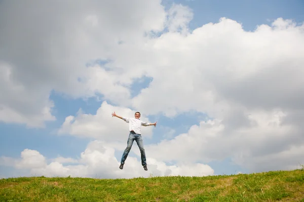 Šťastný Mladý Muž Skákání Proti Pozadí Modré Oblohy — Stock fotografie