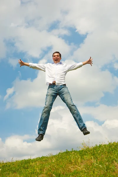 Szczęśliwy młody człowiek - skoki na tle niebieskiego nieba. — Zdjęcie stockowe