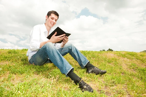 Ευτυχής Διαβάζοντας Ένα Βιβλίο Καθισμένος Στο Πράσινο Γρασίδι — Φωτογραφία Αρχείου