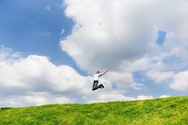 Lycklig man hoppar på ett fält — Stockfoto