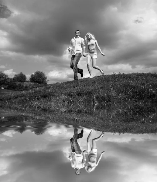 Jovem casal caminhando através do gramado de verão — Fotografia de Stock