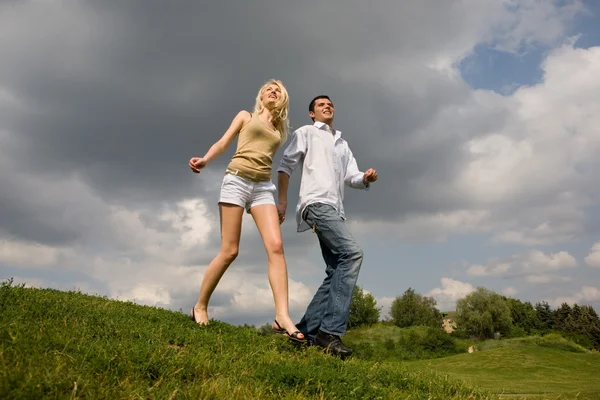 Jeune couple marchant à travers la pelouse d'été — Photo