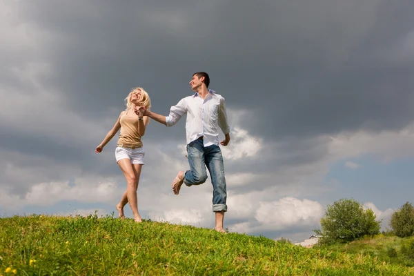 Ungt par promenader genom sommaren gräsmatta — Stockfoto