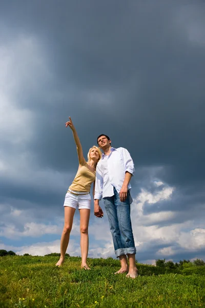 Glückliches junges Paar, das etwas über einer grünen Wiese betrachtet. ma — Stockfoto
