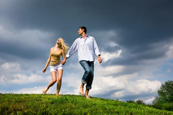Jovem casal caminhando através do gramado de verão — Fotografia de Stock