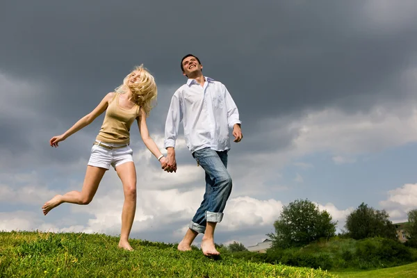 Giovane coppia a piedi attraverso prato estivo — Foto Stock