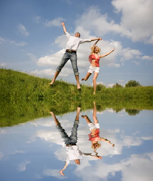 Gelukkig jonge liefde paar - springen onder de blauwe hemel — Stockfoto