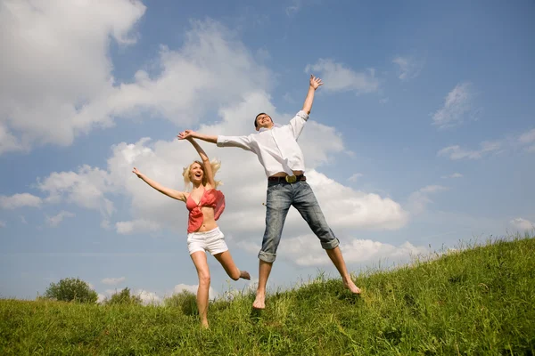 幸せな若い愛のカップル 青い空の下にジャンプ — ストック写真