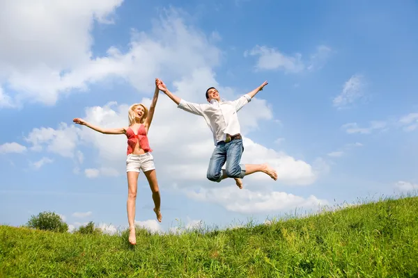 Pareja Joven Feliz Saltando Cielo Sobre Prado Verde — Foto de Stock