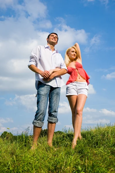 Young couple standing on summer meadow — Stock Photo, Image