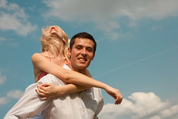 Jonge liefde paar glimlachend onder de blauwe hemel — Stockfoto