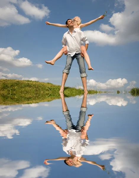 Pár šťastné mladé lásky - skákání pod modrou oblohou — Stock fotografie