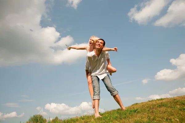 Mladá láska pár usmívá pod modrou oblohou — Stock fotografie
