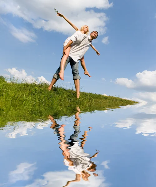 Happy νεαρό ζευγάρι - άλμα στον ουρανό πάνω από ένα πράσινο λιβάδι — Φωτογραφία Αρχείου