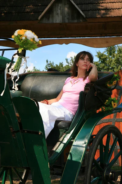 美丽的年轻女子坐在老马车 — 图库照片