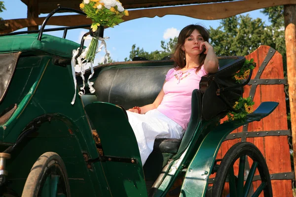 Bella giovane donna siede nella vecchia carrozza — Foto Stock