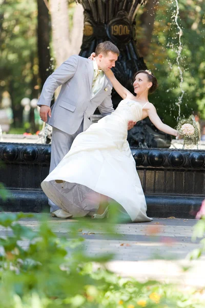 Ženich a nevěsta radosti proti pozadí fontána — Stock fotografie