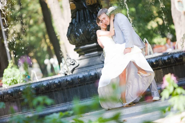 Bruid en bruidegom vreugde tegen achtergrond fontein — Stockfoto