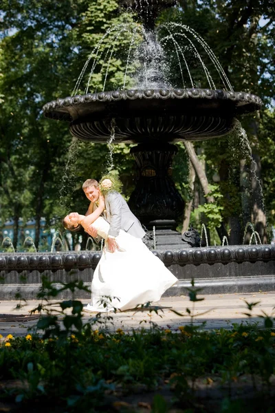 Bräutigam und Braut freuen sich vor Kulisse Brunnen — Stockfoto