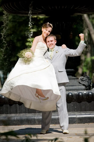Vőlegény és menyasszony öröme ellen a hátteret szökőkút — Stock Fotó