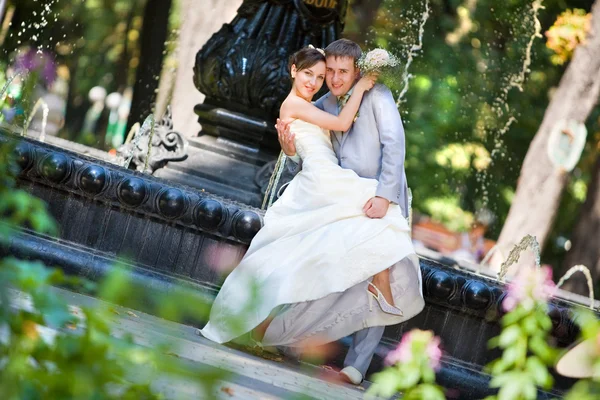 新郎和新娘喜悦反对背景喷泉 在所有的增长 — 图库照片