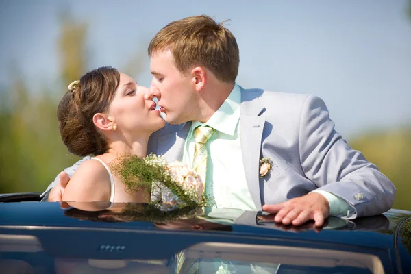 Bride and groom kissing on wedding auto — Stock Photo, Image