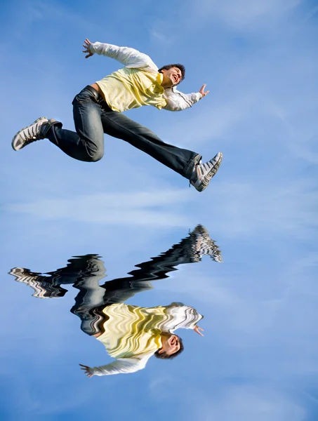 Szczęśliwy młody człowiek - skoki koniec leci w błękitne niebo. — Zdjęcie stockowe