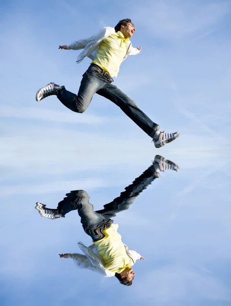 Szczęśliwy młody człowiek - skoki koniec leci w błękitne niebo — Zdjęcie stockowe