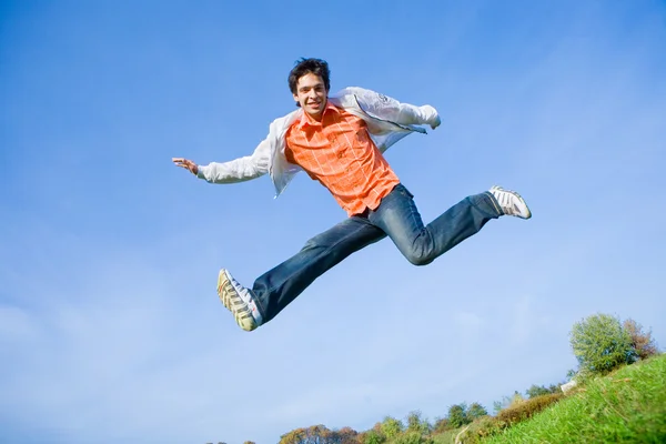 Χαρούμενος νεαρός άνδρας - άλμα με φόντο το γαλάζιο του ουρανού. — Φωτογραφία Αρχείου