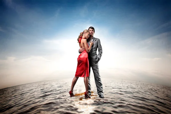 Feliz joven pareja de pie sobre el agua — Foto de Stock