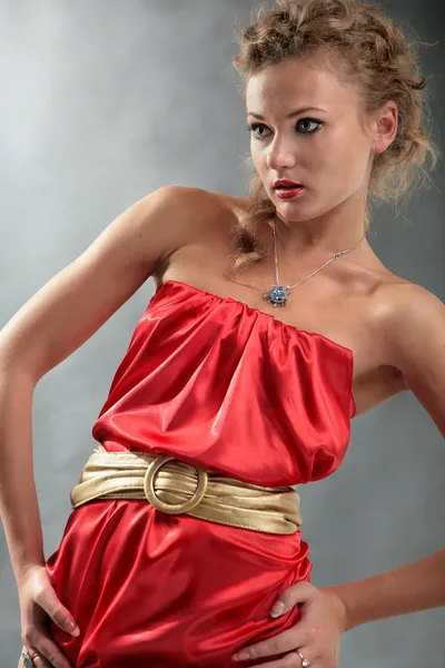 Piękna blondynka w czerwonej sukience i złoty pas oczekuje — Zdjęcie stockowe