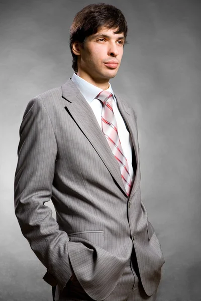 Portrait of the businessman in a grey suit. In studio. — Stock Photo, Image