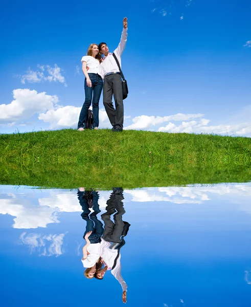 Happy young couple looking at something above a green meadow. Ma — Stock Photo, Image