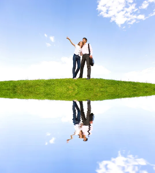 Happy young couple looking at something above a green meadow — Stock Photo, Image