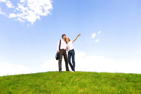 快乐的年轻夫妇看到上面一片绿色的草地的东西 男人用手给看点东西 — 图库照片