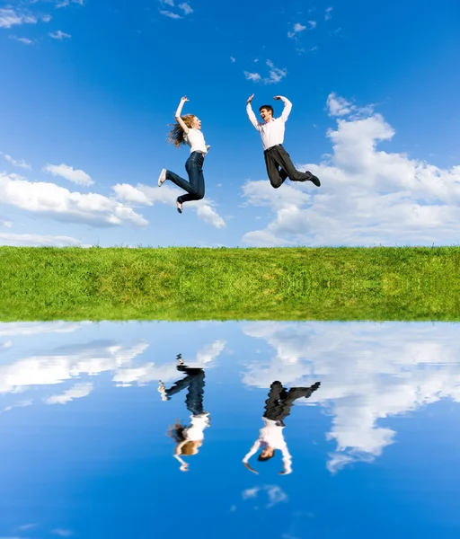 Happy Young Couple - team is jumping in the sky above a green me — Stock Photo, Image