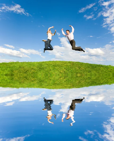 Happy Young Couple - team is jumping in the sky above a green me — Stock Photo, Image