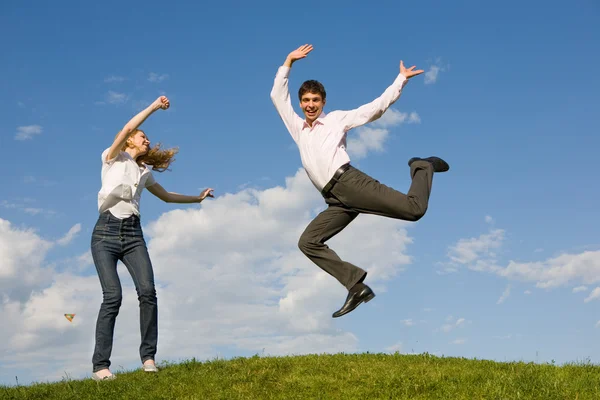 Gelukkige lachende paar springen in blauwe hemel — Stockfoto