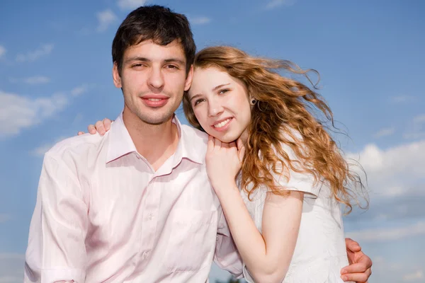 Portrait of a young happy couple against a backdrop of blue sky — Stock Photo, Image