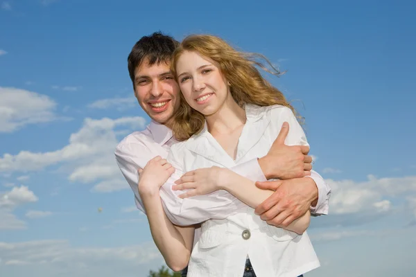 Mavi gökyüzü altında gülümseyen genç aşk Çift — Stok fotoğraf