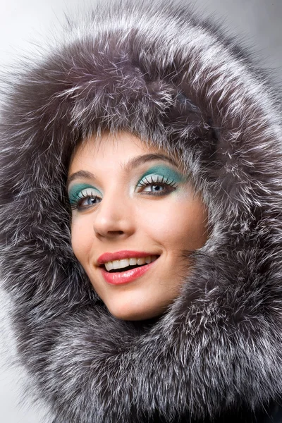 Sorrindo jovem mulher com um capuz de pele — Fotografia de Stock