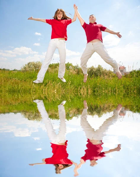 Щаслива молода закохана пара стрибає під блакитним небом — стокове фото