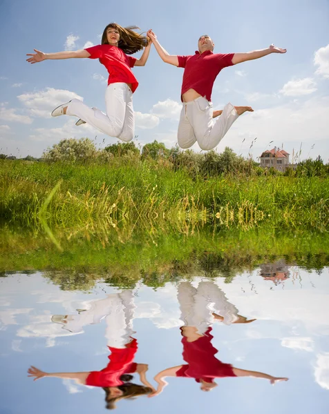 Happy Young Love Couple Jumping Blue Sky Reflected Water — 스톡 사진