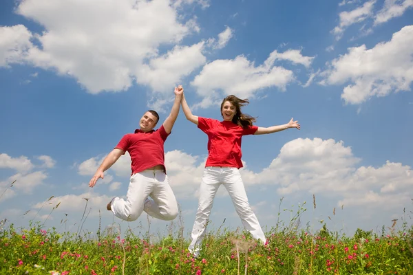 Happy Young love Couple - jumping under blue sky — Stock Photo, Image