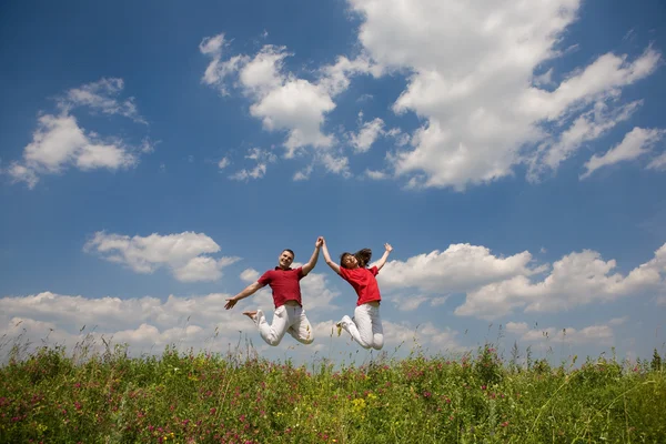 Boldog fiatal szerelmes pár - ugrás, kék ég alatt — Stock Fotó