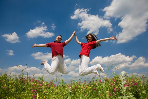 幸せな若い愛のカップル 青い空の下にジャンプ — ストック写真